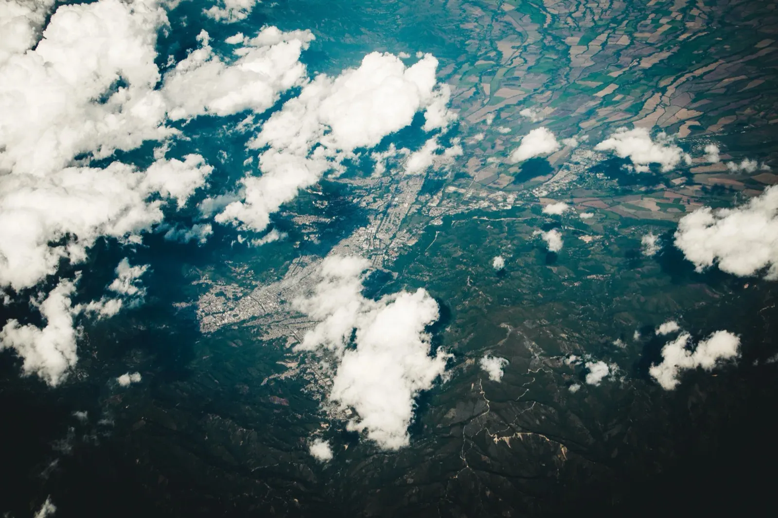 A broken cumulus deck over a valley town and its fields
